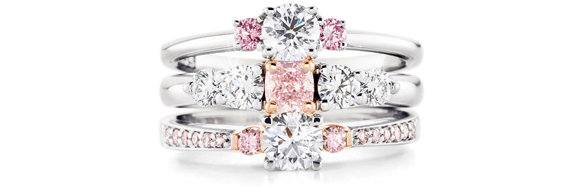 A stack of diamond rings in a trio-style featuring central pink diamonds and pink side diamonds