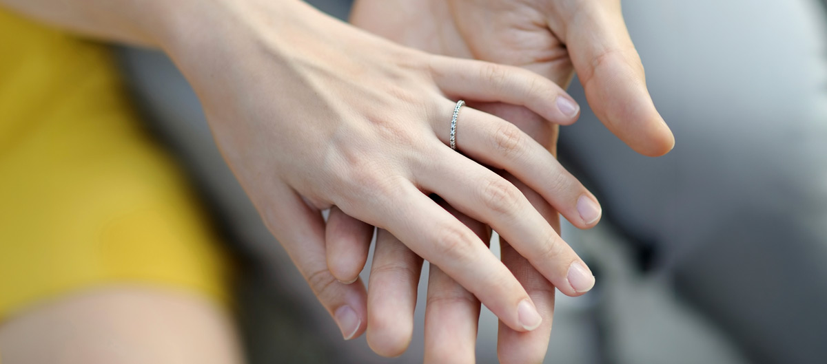Person discreetly measuring their partner’s ring finger to determine their ring size